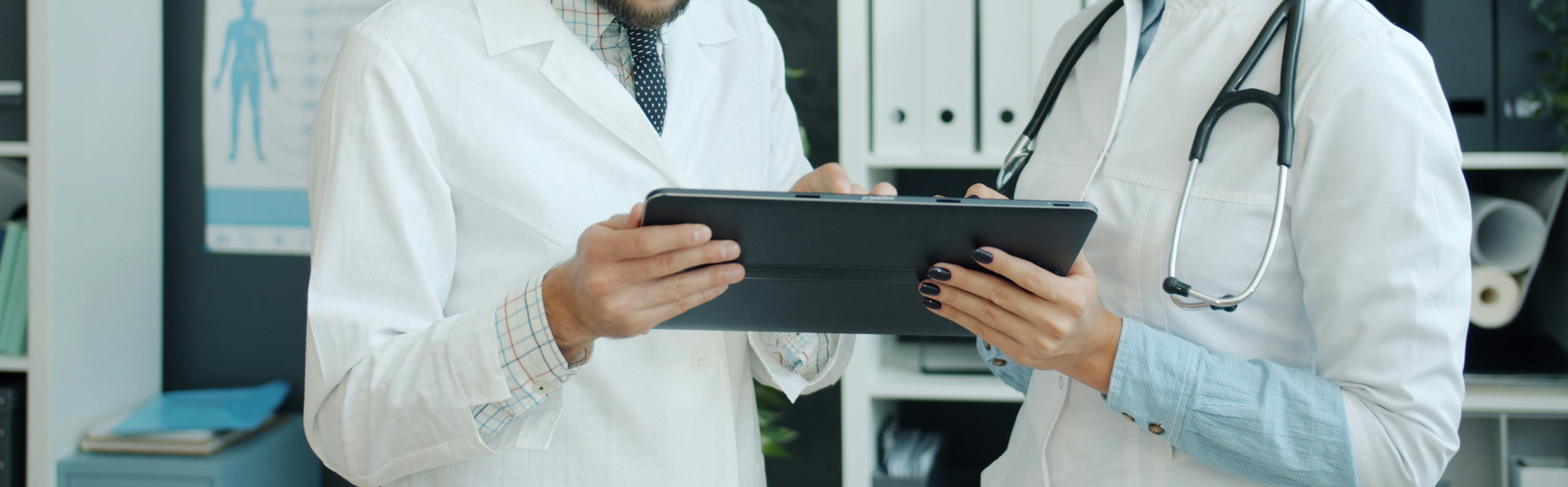 two health care workers holding a tablet.