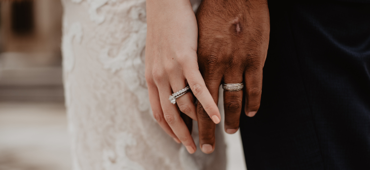 Woman and man holding hands with marriage rings